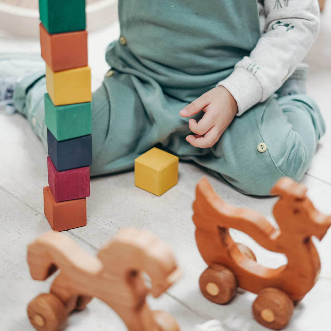 A toddler playing with wooden toys on the floor